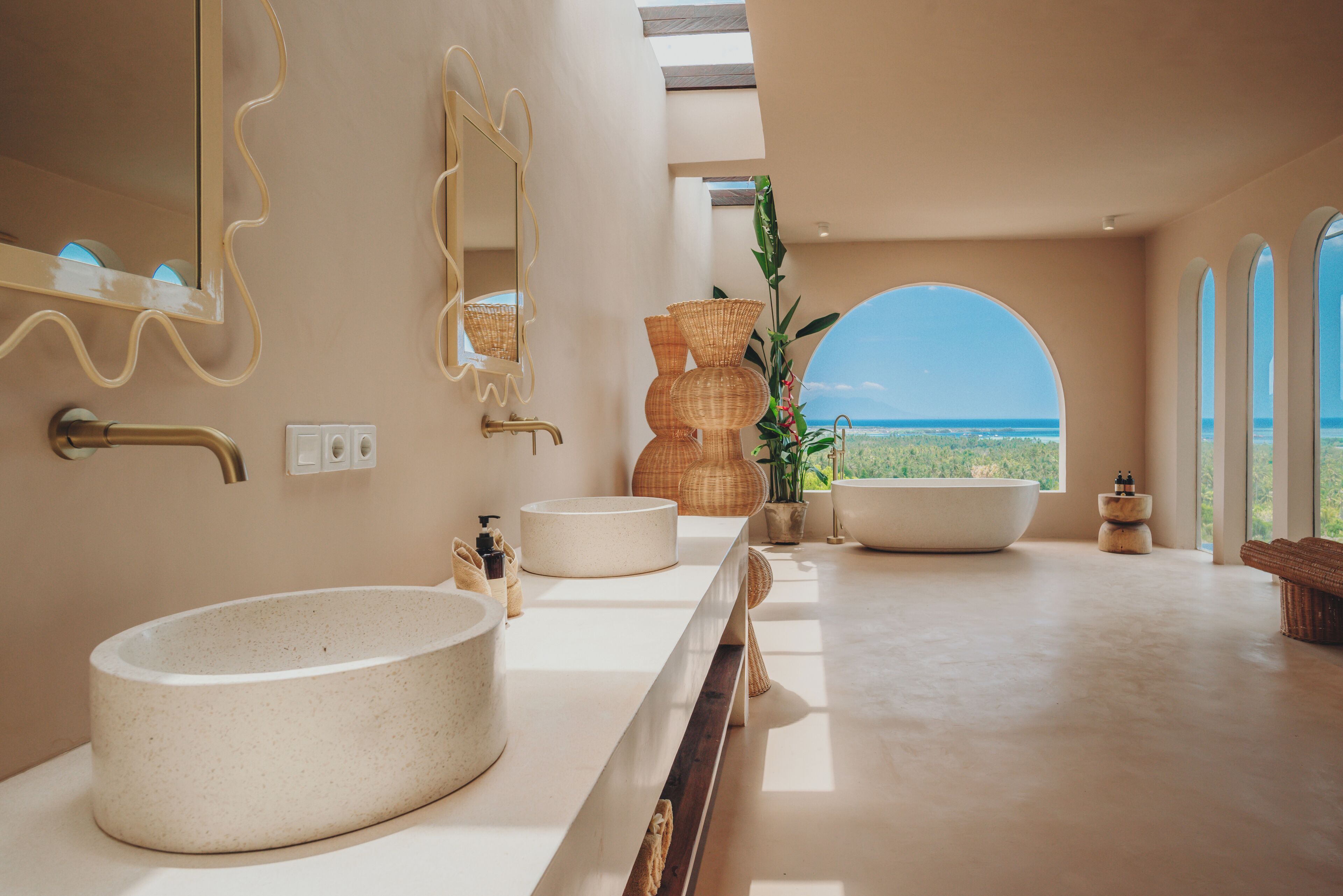 Un baño moderno con un lavamanos grande y redondo, un espejo y vistas al océano.