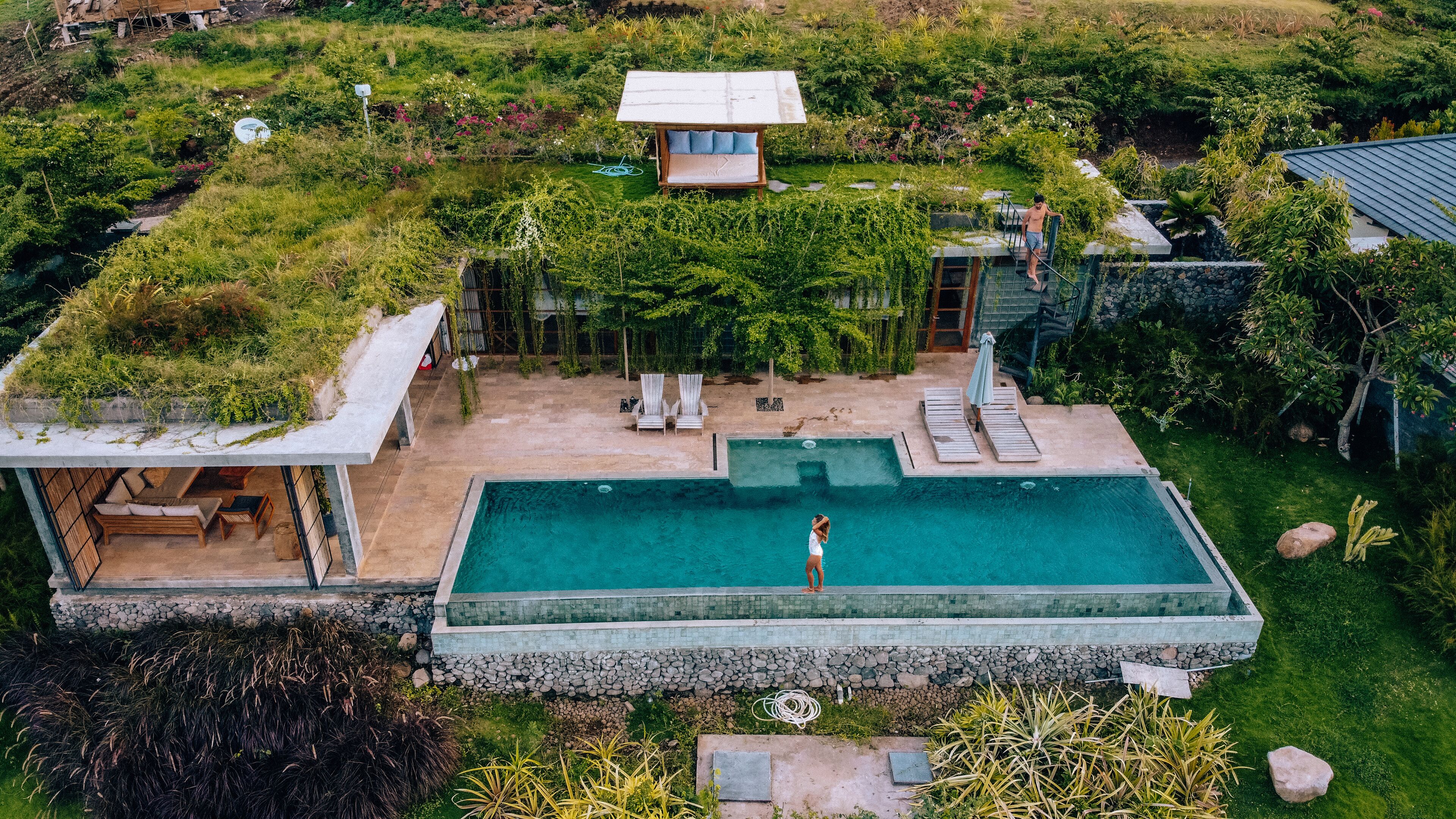 An aerial view of a property with a swimming pool, outdoor seating, and lush greenery.