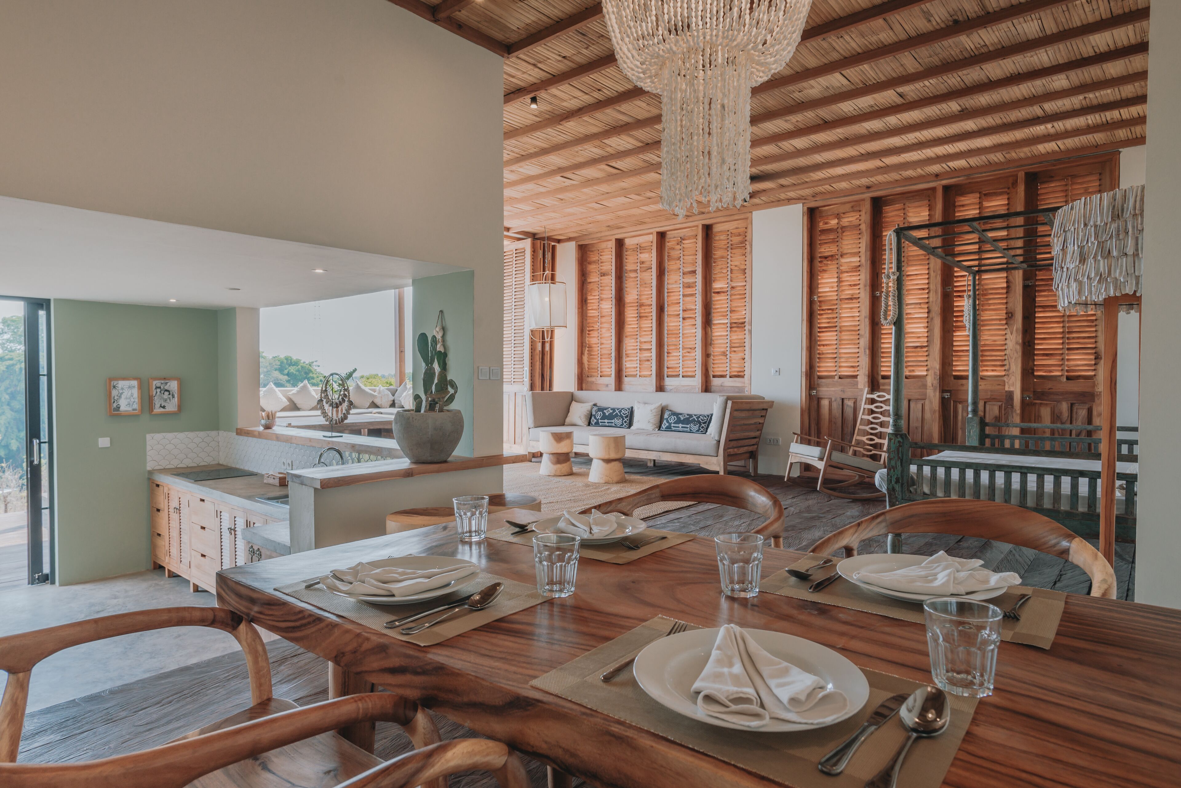 Un coin repas avec une table en bois dressée pour quatre personnes, entourée de chaises en bois.