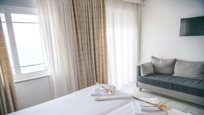 A hotel room with a bed, a sofa, and a TV on the wall. - Maria Plomari Apartments (Lesvos)