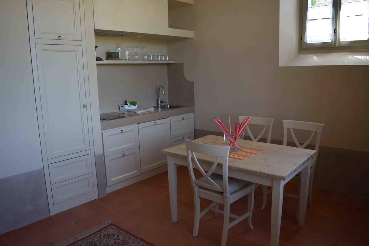 A compact kitchen with white cabinets, a sink, and a dining table with chairs.
