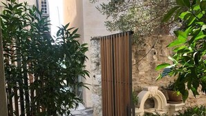 A courtyard with a wooden gate, potted plants, and a stone wall. - Heritage Hotel 19 (Split)