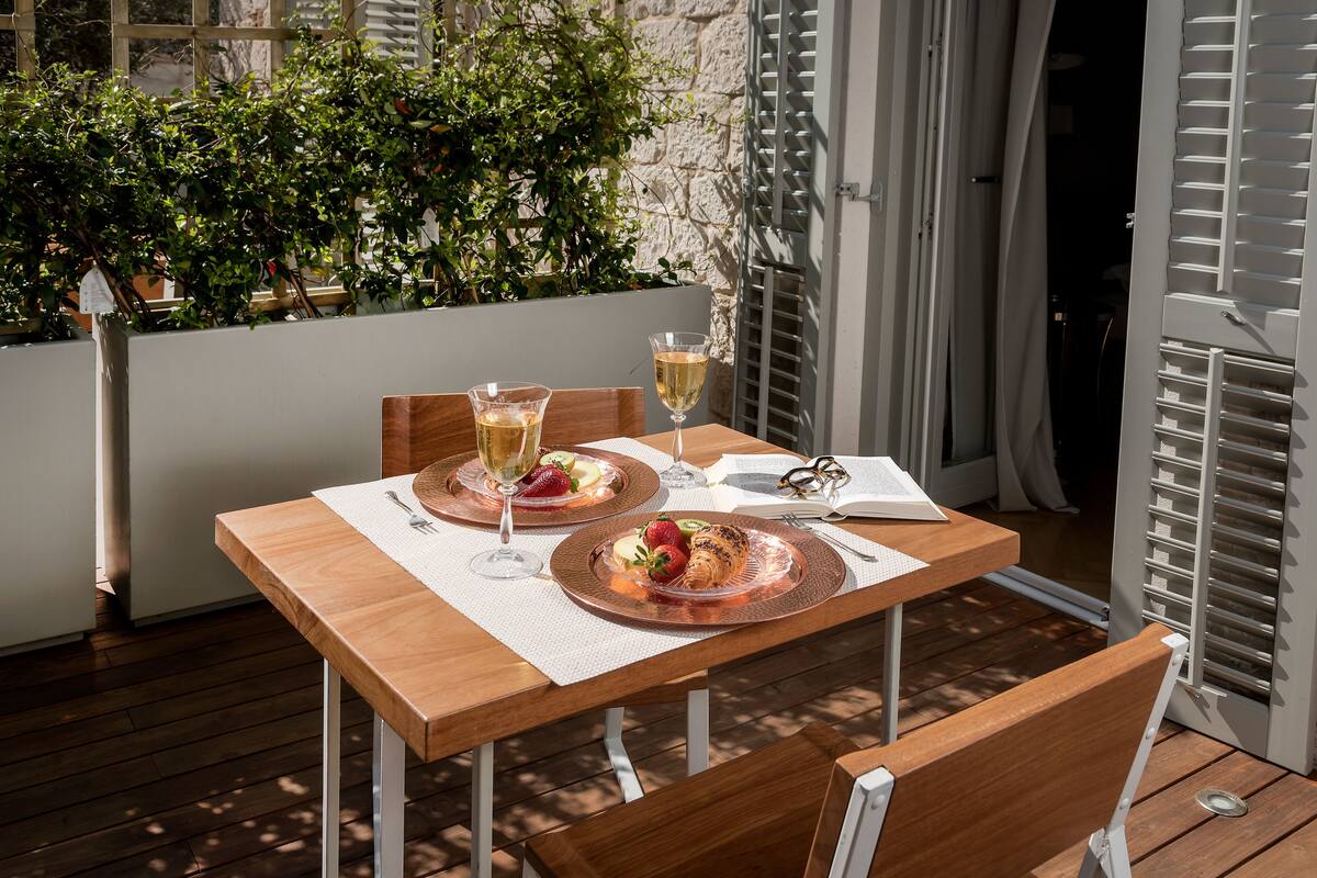A wooden table set with plates of food, glasses of wine, and cutlery.