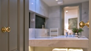 A modern bathroom with a marble countertop, a sink, and a bench. - Heritage Hotel 19 (Split)