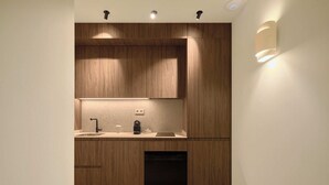 Une cuisine moderne avec des meubles en bois, un lave-vaisselle encastré et un plan de travail doté d’un évier et d’une bouilloire.