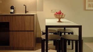 Une cuisine moderne avec des meubles en bois, un four encastré et un coin repas comprenant une table et quatre chaises.