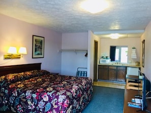 A hotel room with a bed, bedside lamps, a desk with a computer, and a microwave.