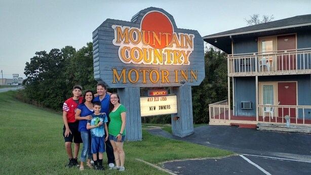 Une famille pose devant l’enseigne d’un motel.