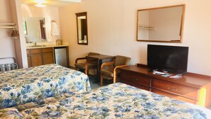 Une chambre d’hôtel avec deux lits, un bureau, une télévision et un miroir.