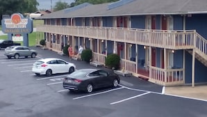 Un motel composé d’un bâtiment à deux étages, d’un espace de stationnement couvert et d’une enseigne indiquant qu’il s’agit d’un établissement proposant des hébergements pour les automobilistes.