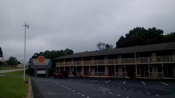 A motel with a large sign, a parking lot, and a building with a balcony.