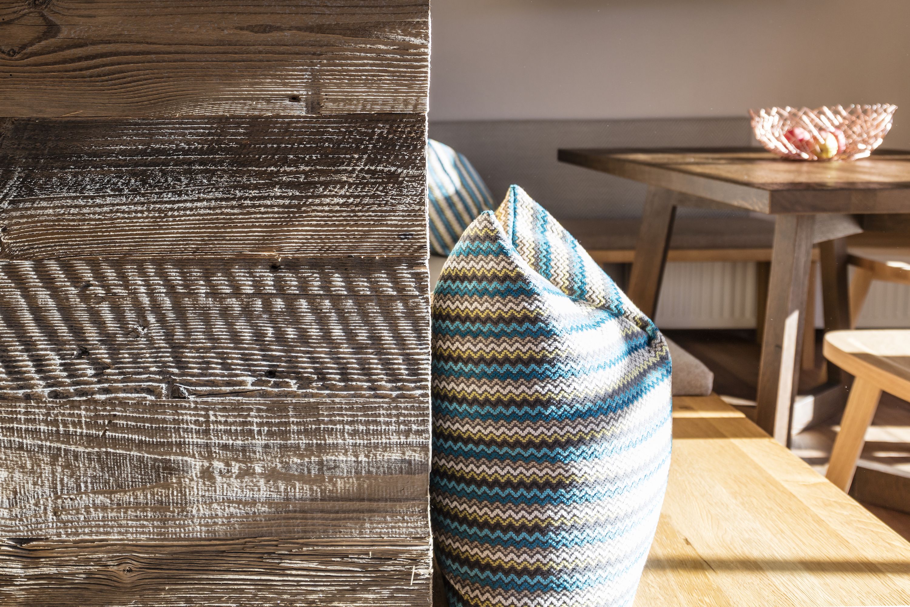 A wooden textured wall and a patterned bean bag chair in a room with a wooden table and chairs.