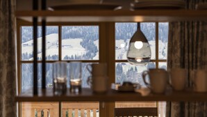 A view through a window with a wooden interior, including a shelf with glassware and plates. - Alpbach Lodge Chalet Superior (Alpbach)