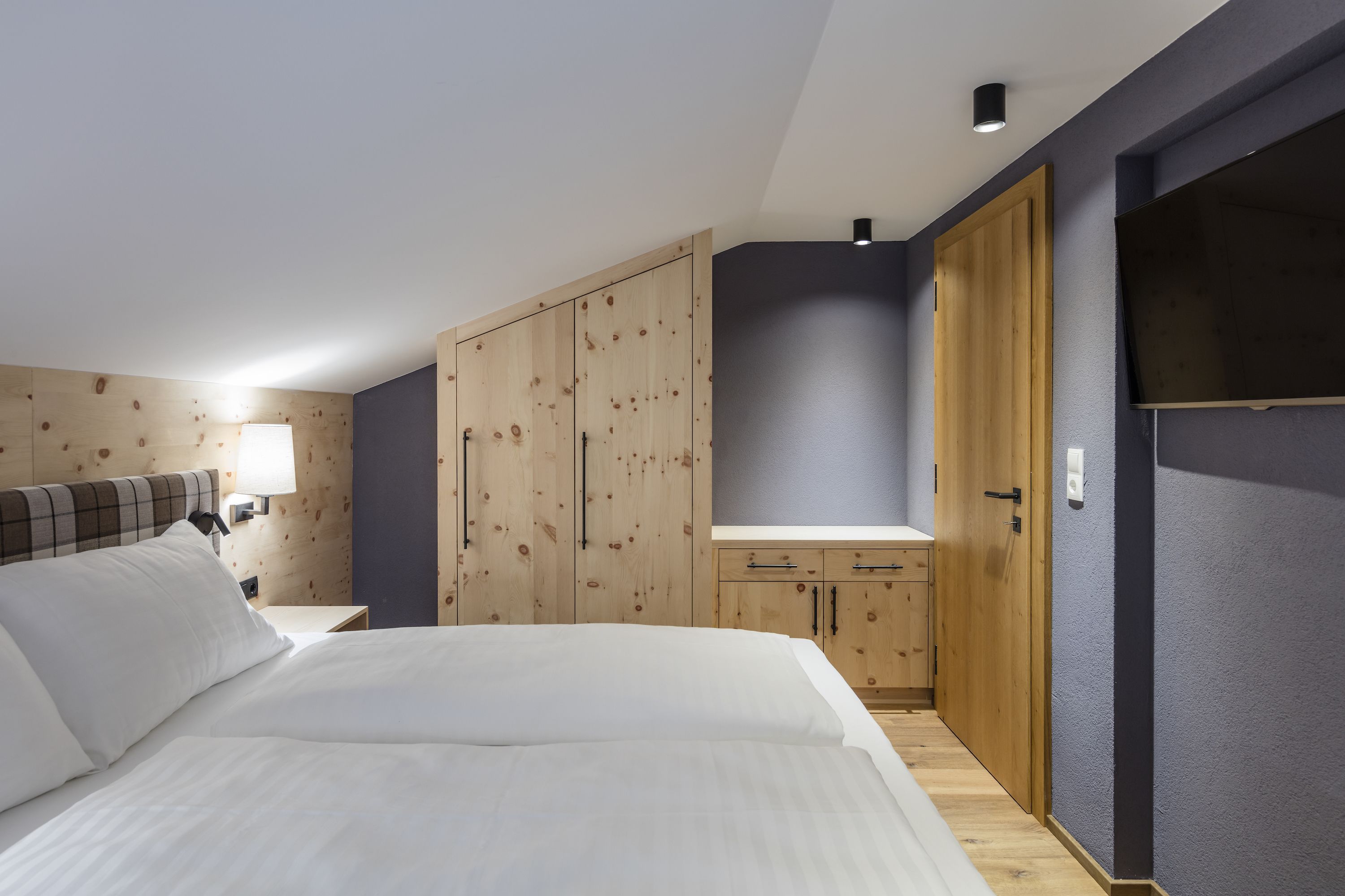 Una camera da letto con un letto, un armadio in legno e un comodino con una lampada.