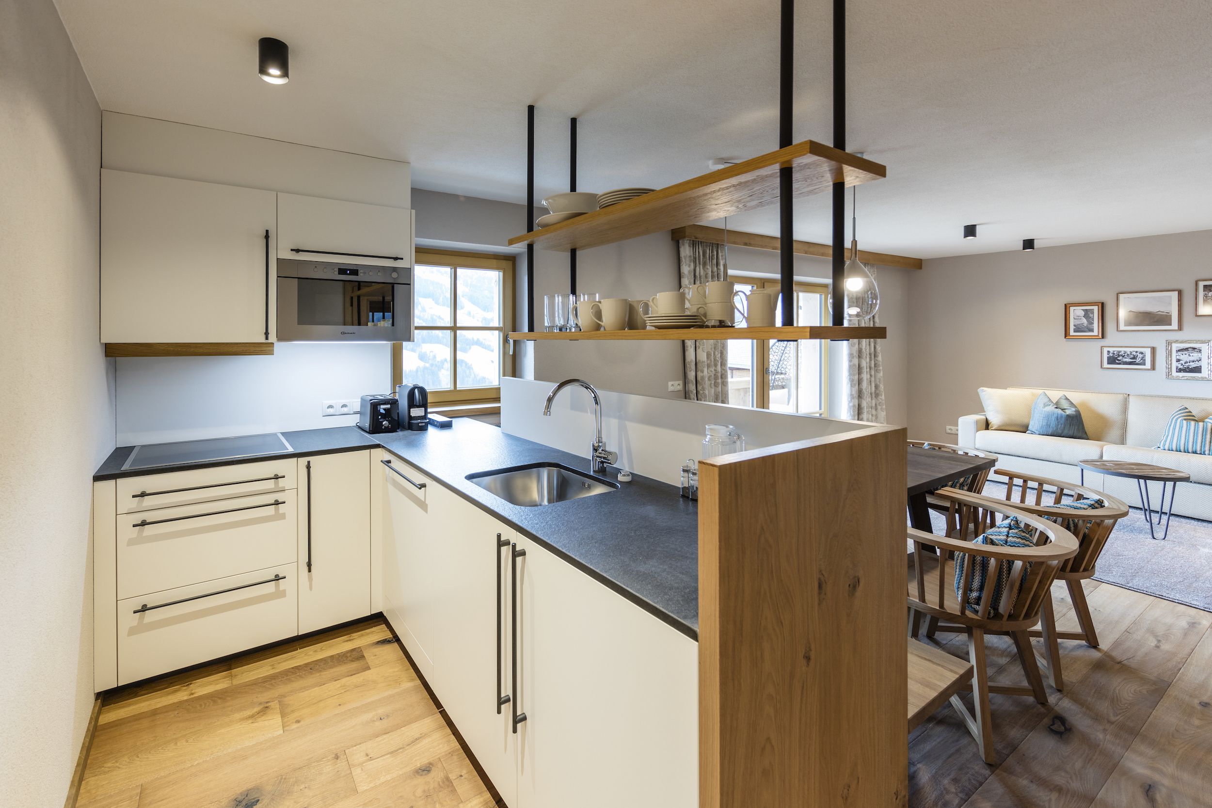 A modern kitchen with a central island, built-in appliances, and a dining area with wooden chairs.
