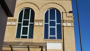 A hotel with a prominent clock tower, large arched windows, and a sign reading "HOTEL HORUS". - VTZ Orús Factory Hotel - Parking Muy Económico (Zaragoza)