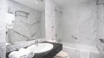 Een moderne badkamer met een marmeren wastafel, een douche met glazen wanden en een wit toilet.