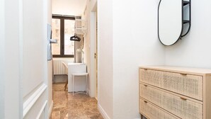 A hallway with a white wall, a wooden dresser, and a mirror. - VTZ Orús Factory Hotel - Parking Muy Económico (Zaragoza)