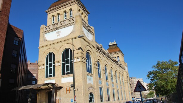 A historic building with a prominent clock tower, a large sign reading "HOTEL DE SAINT-PAUL," and a pedestrian crossing sign. - VTZ Orús Factory Hotel - Parking Muy Económico (Zaragoza)