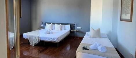 Une chambre d’hôtel avec deux lits, un plancher en bois, un grand miroir et un tableau encadré au mur.