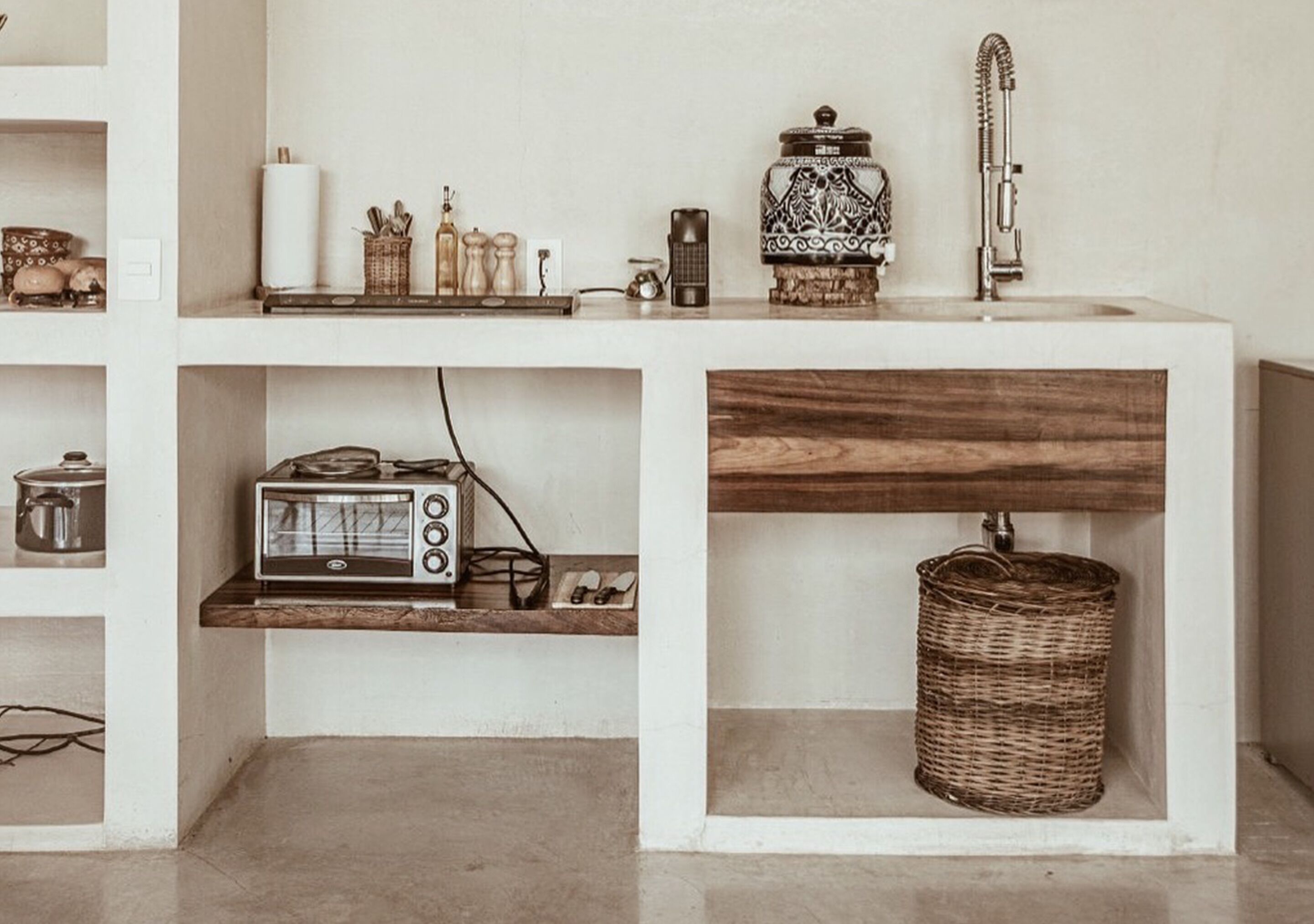 A kitchen with a white countertop, a vintage radio, a toaster, a wicker basket, and a decorative ceramic jar.