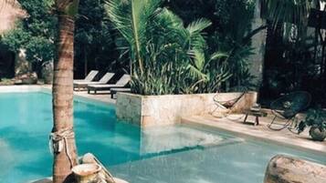 A pool area with lounge chairs, palm trees, and a clear blue pool.