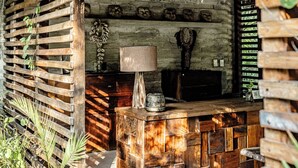 Una cabaña rústica de madera con techo de paja, un banco de madera y una pared decorada con máscaras.