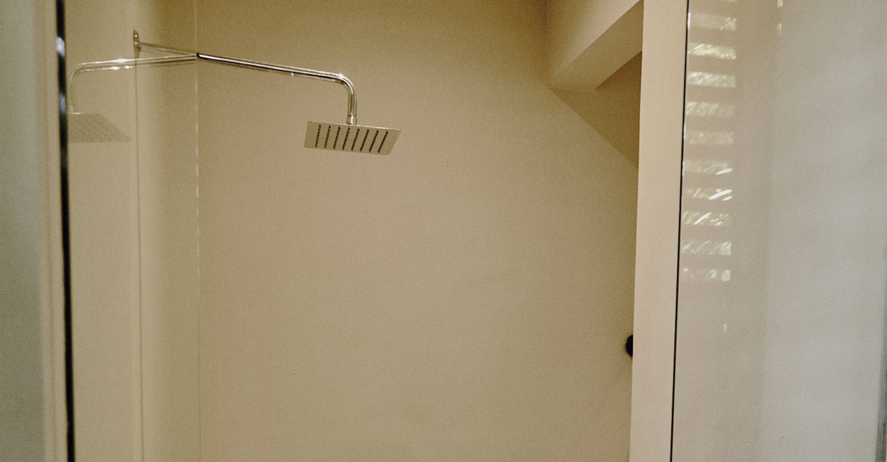A shower with a handheld showerhead and a wall-mounted control panel.
