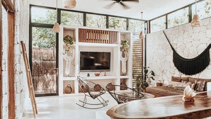 Amplia sala de estar con un televisor grande, muebles de madera y vistas a zonas verdes.