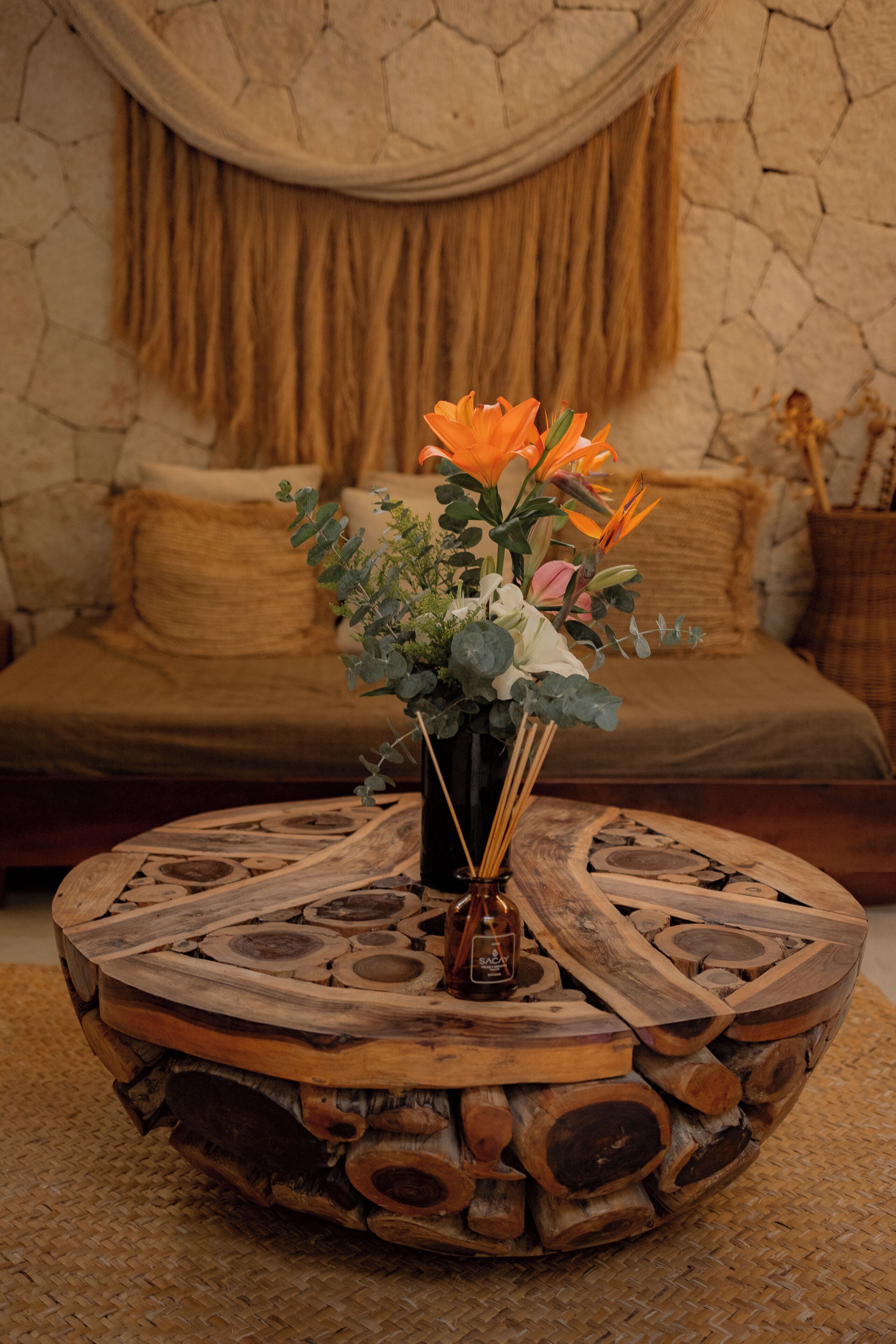 A round wooden coffee table with a vase of flowers.