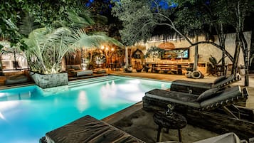 Una piscina al aire libre, sombrillas, sillones reclinables de piscina