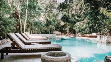Zona de piscina con sillones de descanso y una chimenea de piedra.