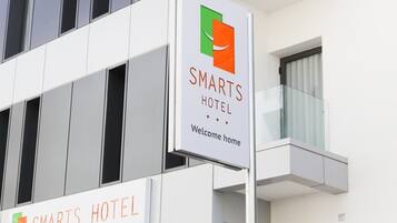 A modern building with a sign that reads "SMARTS HOTEL Welcome home."
