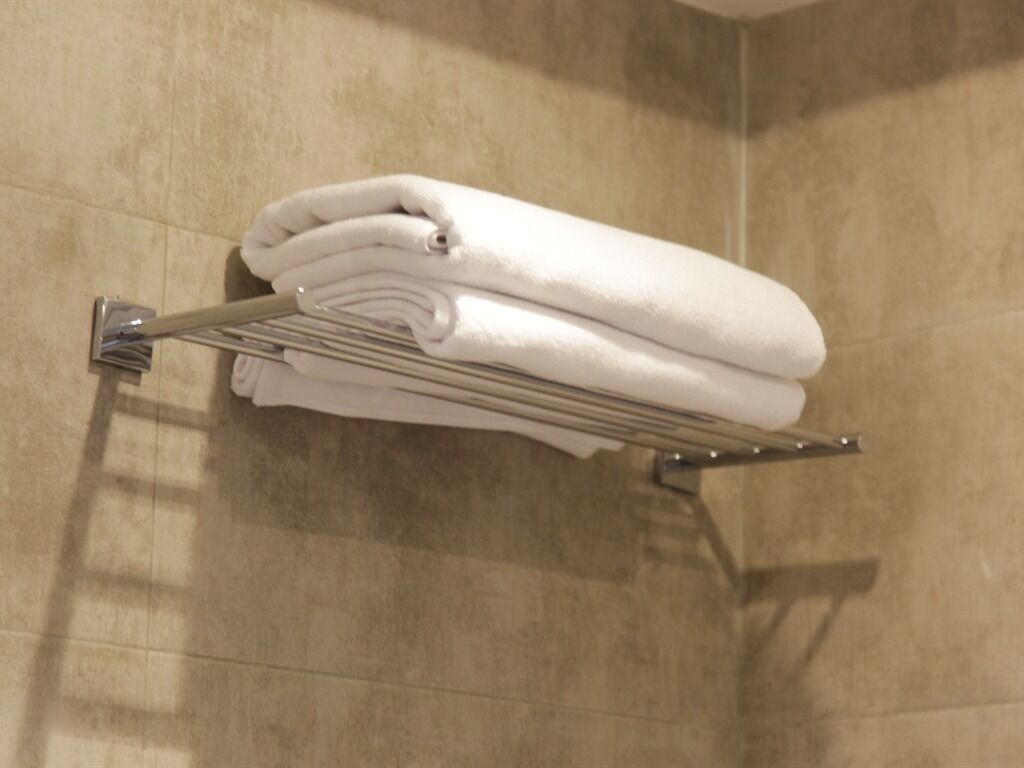 A bathroom with a towel rack holding folded towels.