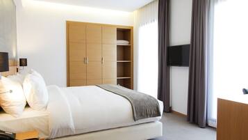 Una habitación de hotel moderna con una cama grande, un armario de madera, un televisor de pantalla plana y un escritorio.