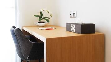 A wooden desk with a white bowl containing a plant, a tissue box, and a red pen.