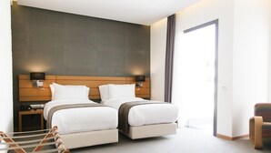 A modern hotel room with a large bed, bedside tables, a chair, and a view of the outside. - Smarts Hotel (Rabat)