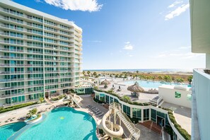 A resort with a large swimming pool, a water slide, and a view of the ocean. - Caribe Unit C509 (Orange Beach)