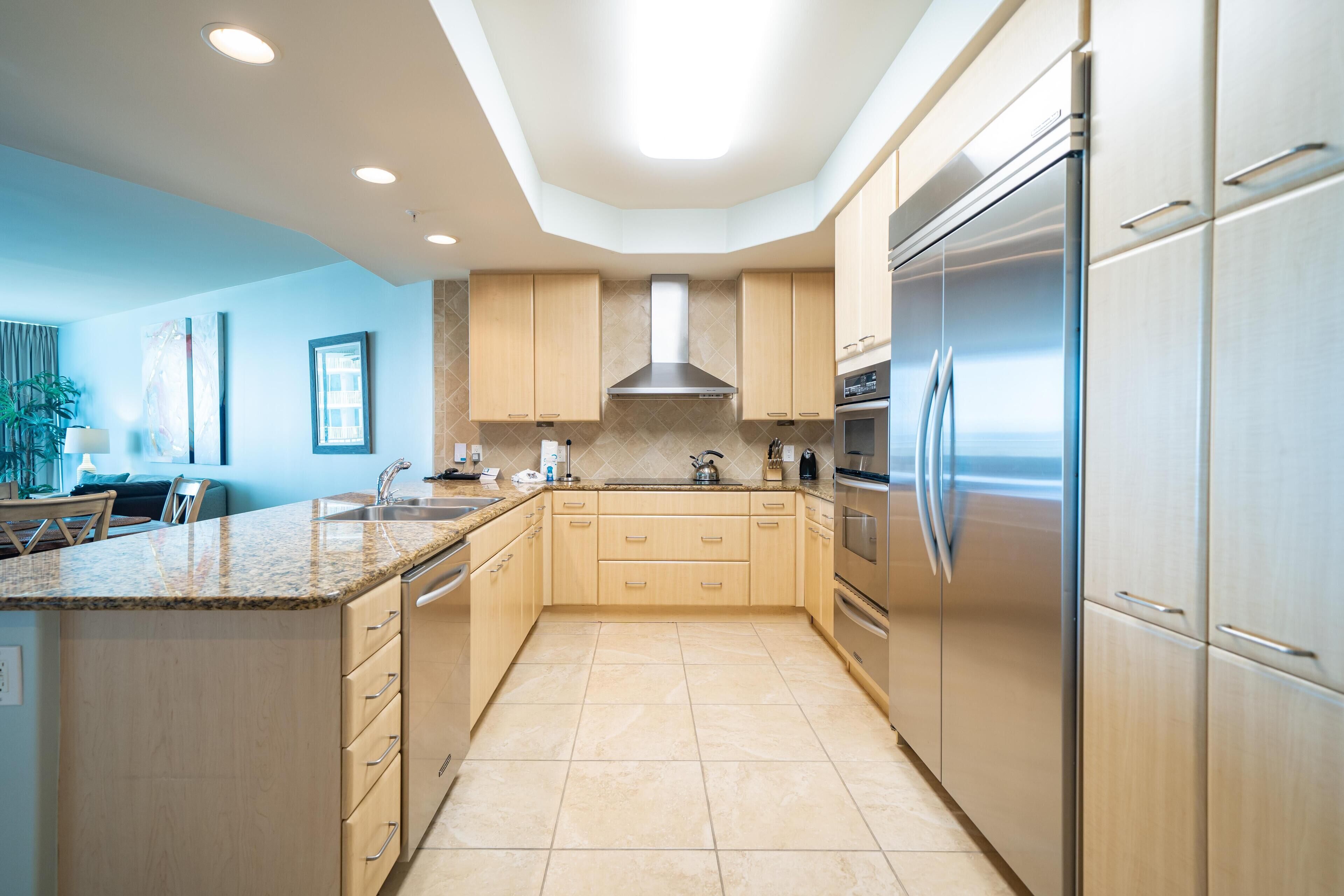 A modern kitchen with light wood cabinets, stainless steel appliances, and a central island.