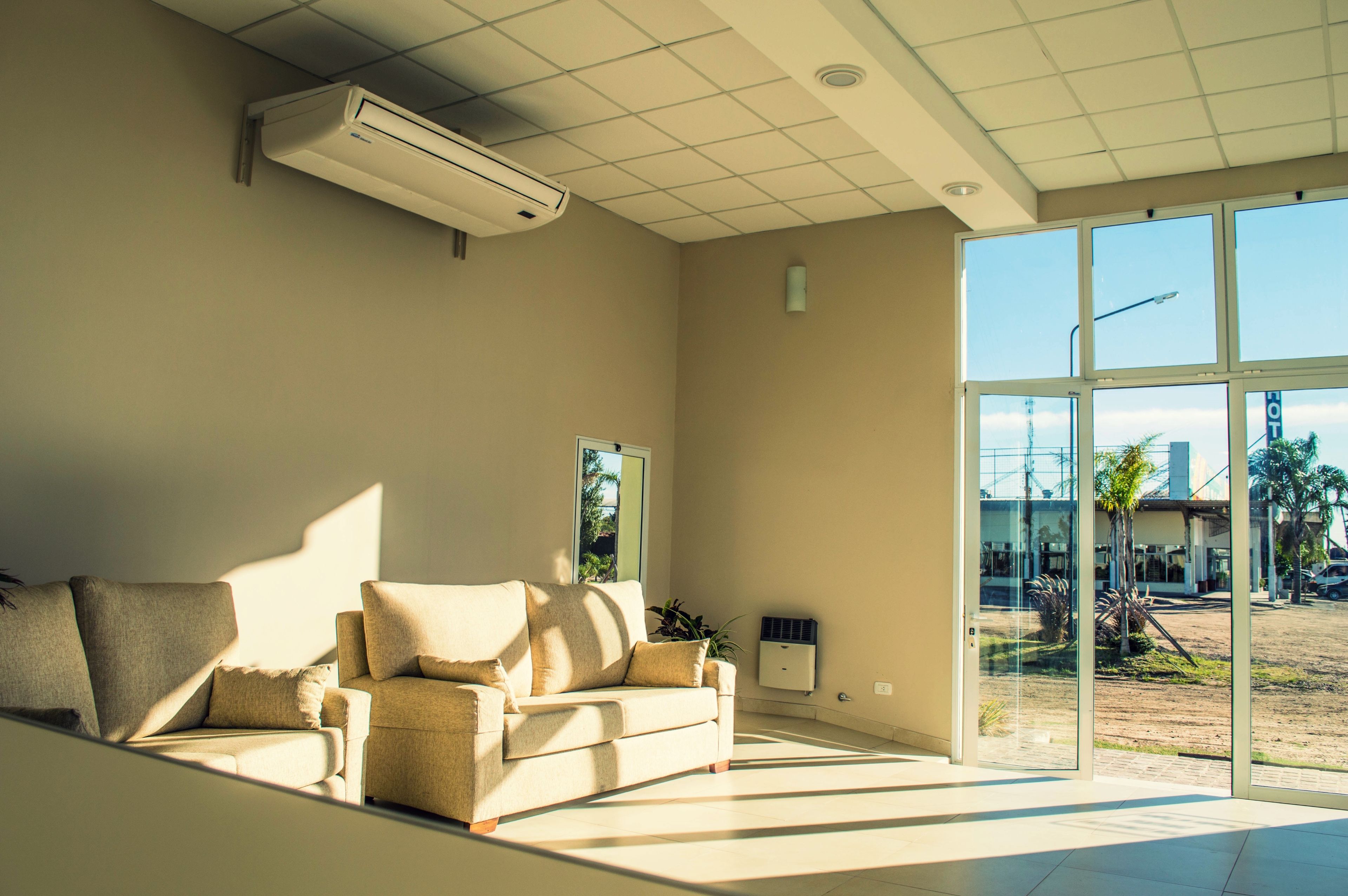 Una stanza moderna con un divano color beige, un'ampia finestra e un condizionatore.