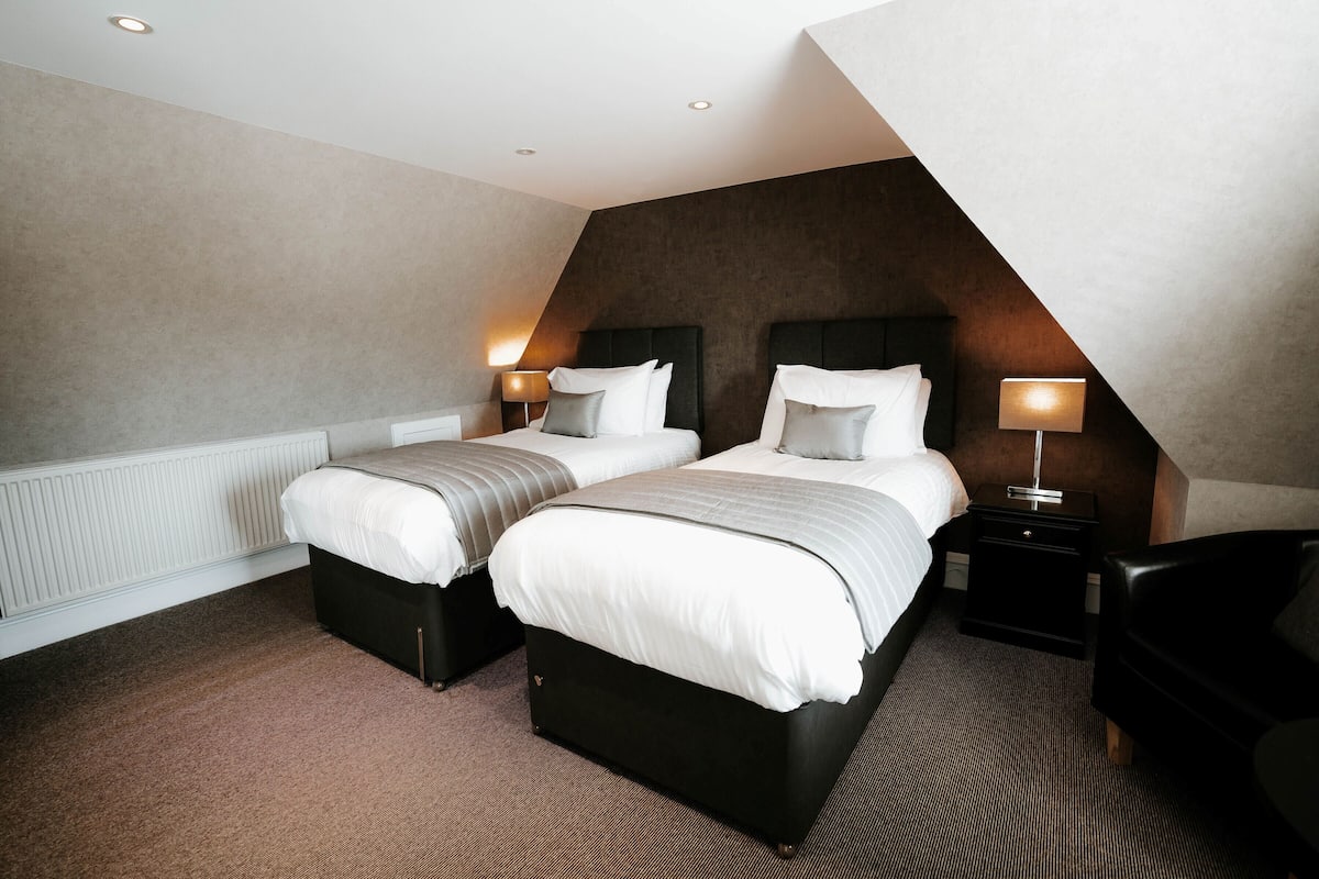 Ein modernes Hotelzimmer mit zwei Betten, einem Schreibtisch und einem Stuhl.