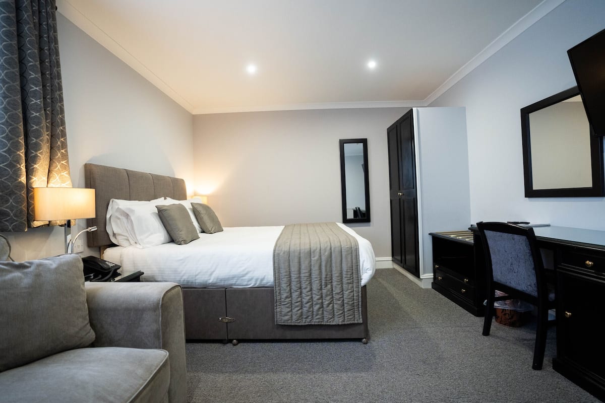 Ein Hotelzimmer mit einem Bett, einem Schreibtisch, einem Stuhl, einer Lampe und einem Kleiderschrank.