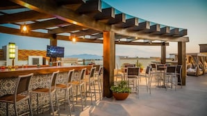 A rooftop bar with a view of the mountains, bar stools, and a television screen. - Fiesta Inn Puerto Vallarta Isla (Puerto Vallarta)