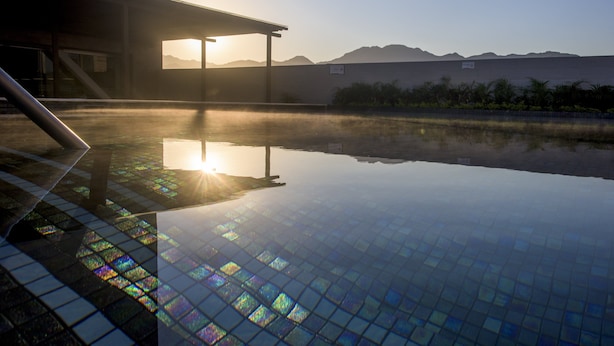 A clear pool with a tiled floor, a covered area, and mountains in the background. - Fiesta Inn Puerto Vallarta Isla (Puerto Vallarta)