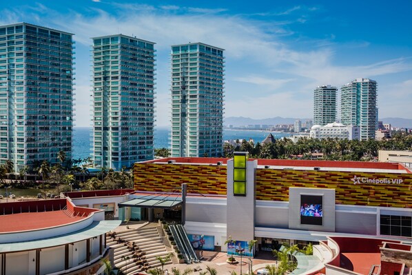 Um hotel moderno com muitos andares, um átrio central e vista para o mar.