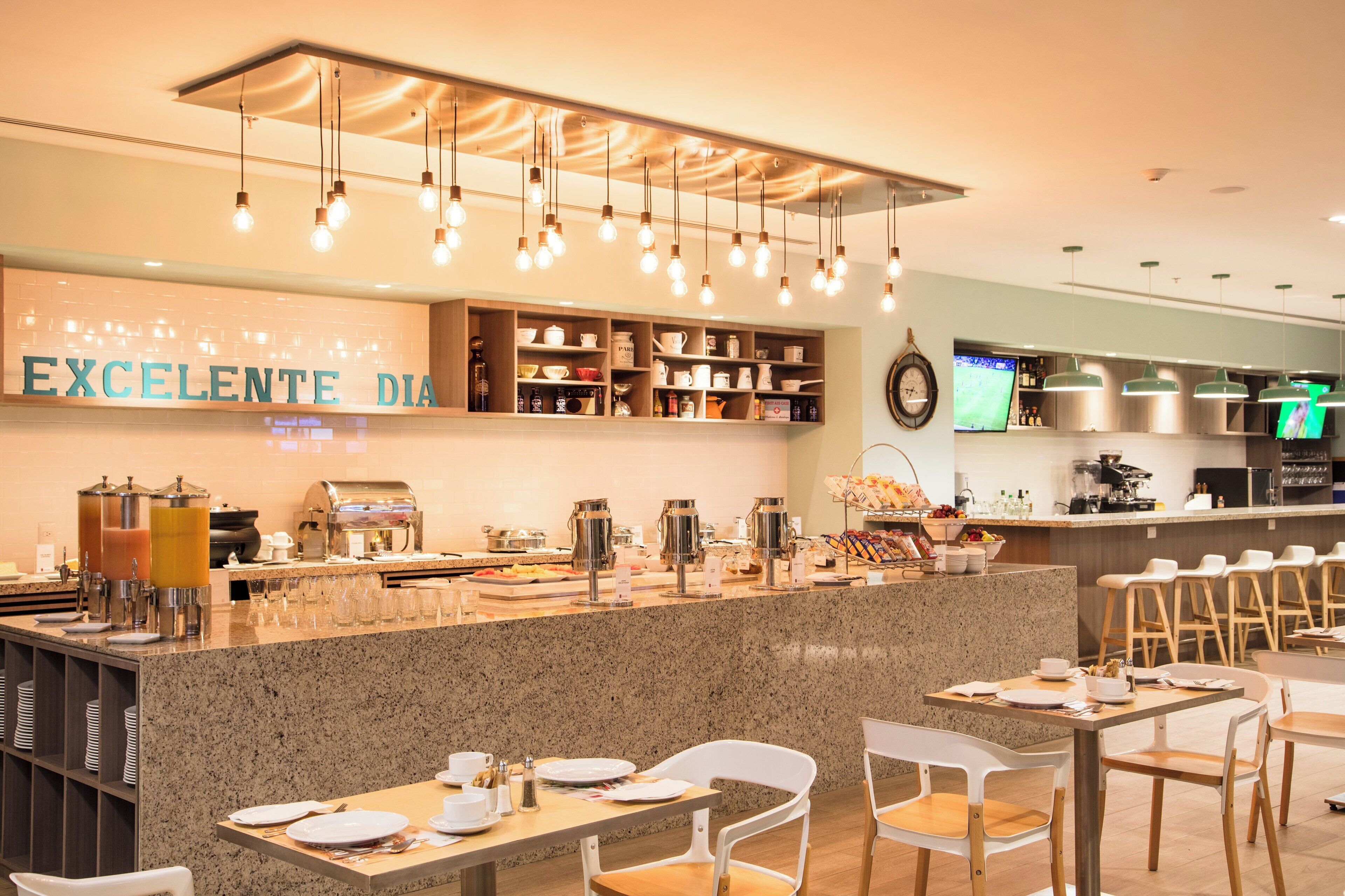 A breakfast bar with a variety of food and drink options, a coffee machine, and seating areas with tables and chairs.