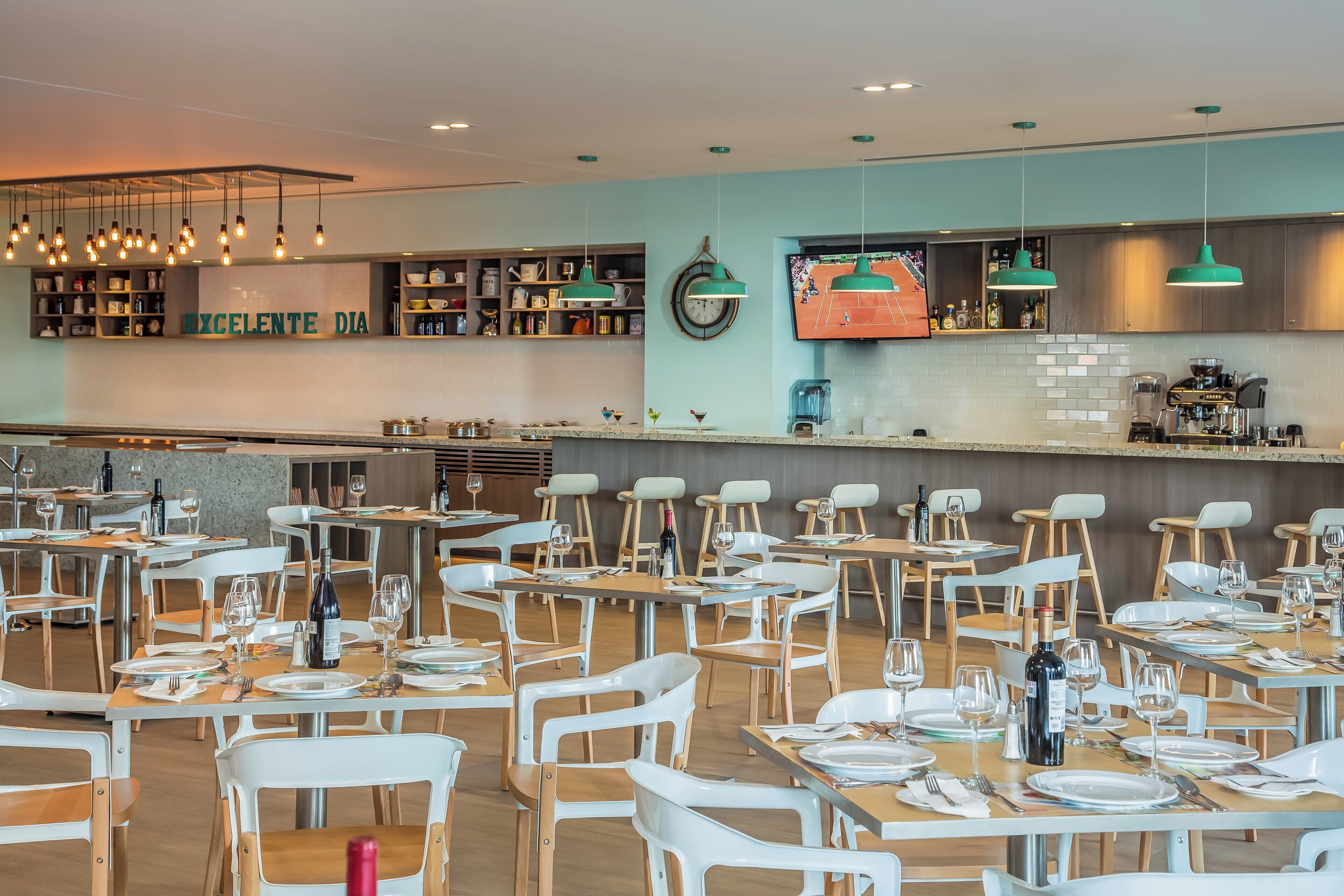 A restaurant with tables set for dining, a bar area, and a kitchen visible in the background.