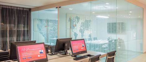 A modern office with glass walls, multiple computer monitors, and a wooden conference table.