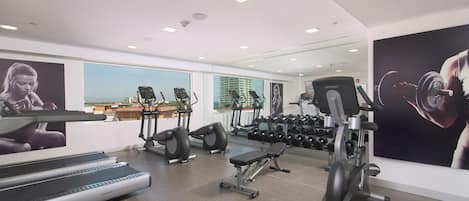A modern gym with treadmills, elliptical machines, and free weights.
