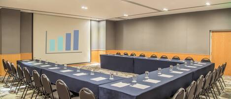 A conference room with a long table, chairs, and a presentation screen.